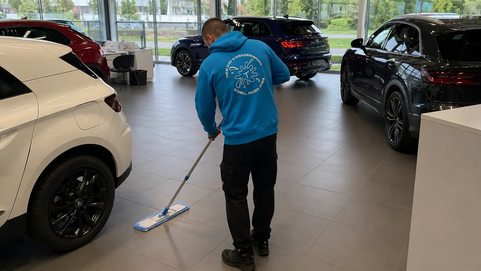 Mitarbeiter wischt den Showroomboden eines Autohauses in Bamberg
