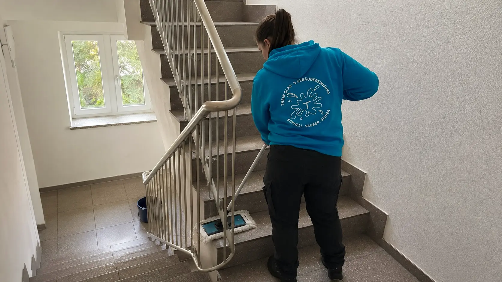 Mitarbeiterin reinigt Stufen in einem Treppenhaus in Bamberg