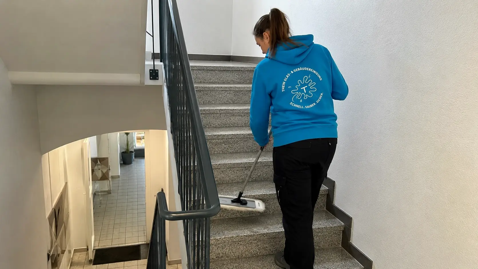 Mitarbeiterin reinigt Stufen in einem Treppenhaus in Bamberg