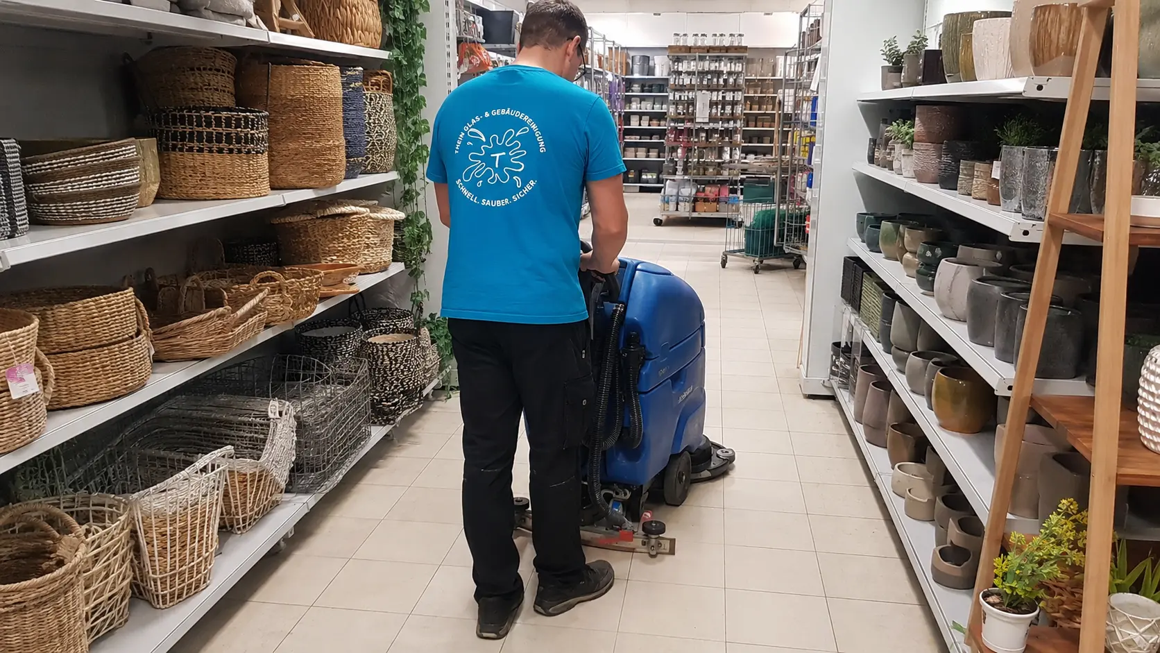 Mitarbeiter reinigt den Gang einer Verkaufsfläche mit einer Scheuersaugmaschine in Bamberg