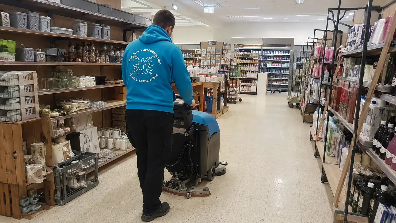 Mitarbeiter reinigt den Boden eines Ladengeschäfts mit einer Scheuersaugmaschine in Bamberg